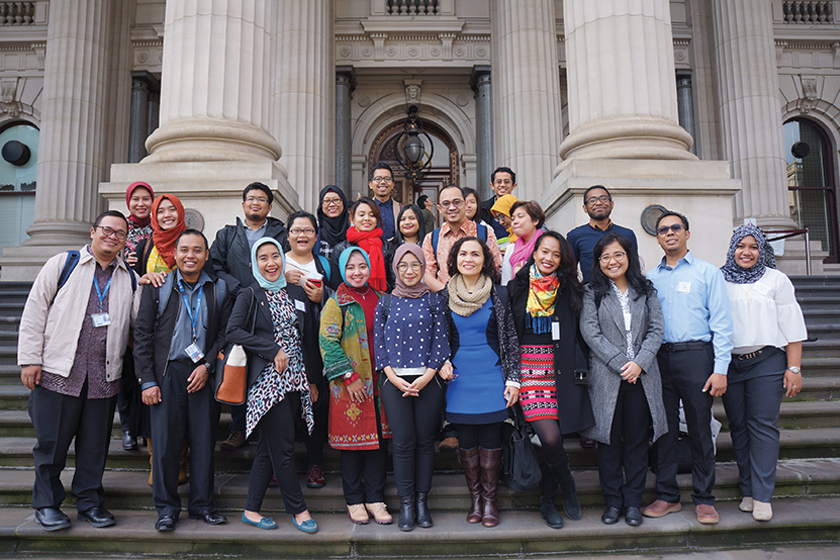 A group of smiling students being photograph in front of building